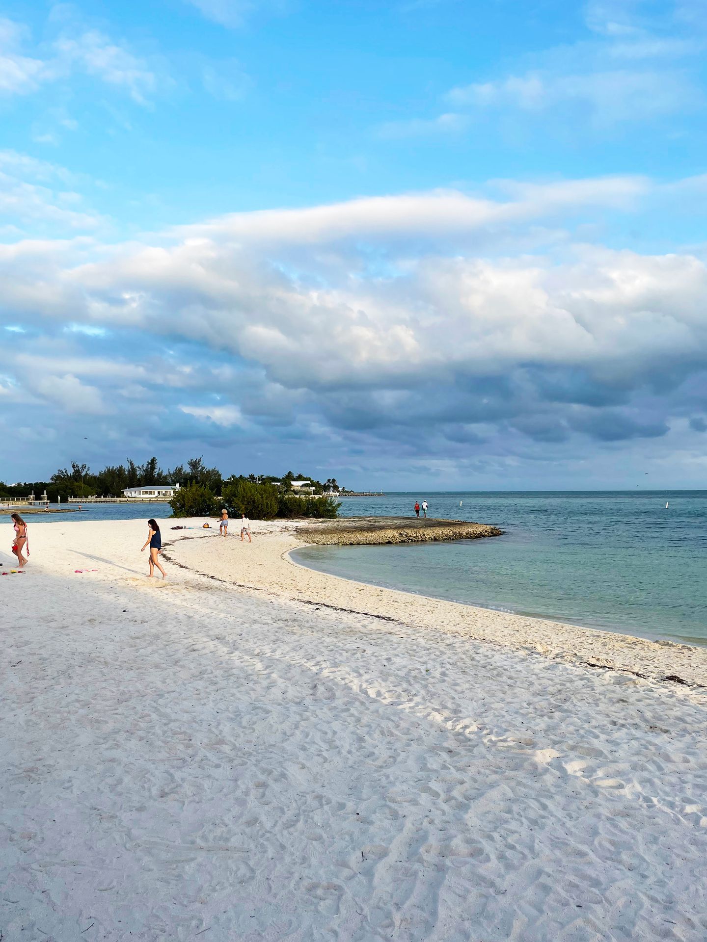 Looking at the sand and ocean of Sombrero Beach as a few people walk by