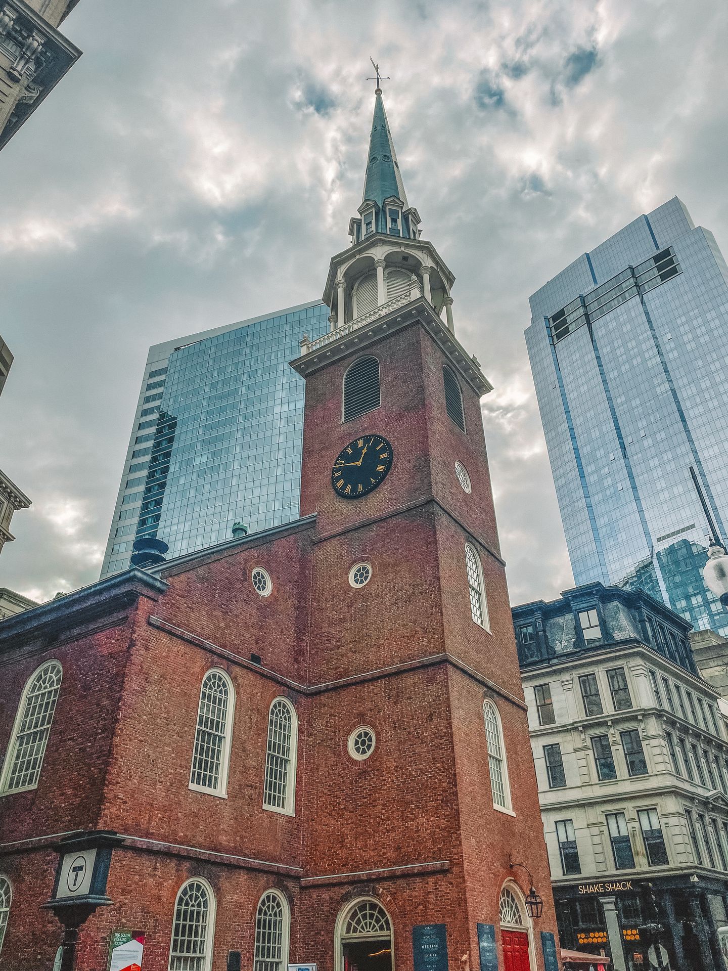 Looking up at a brick building with a clock and a point at the top
