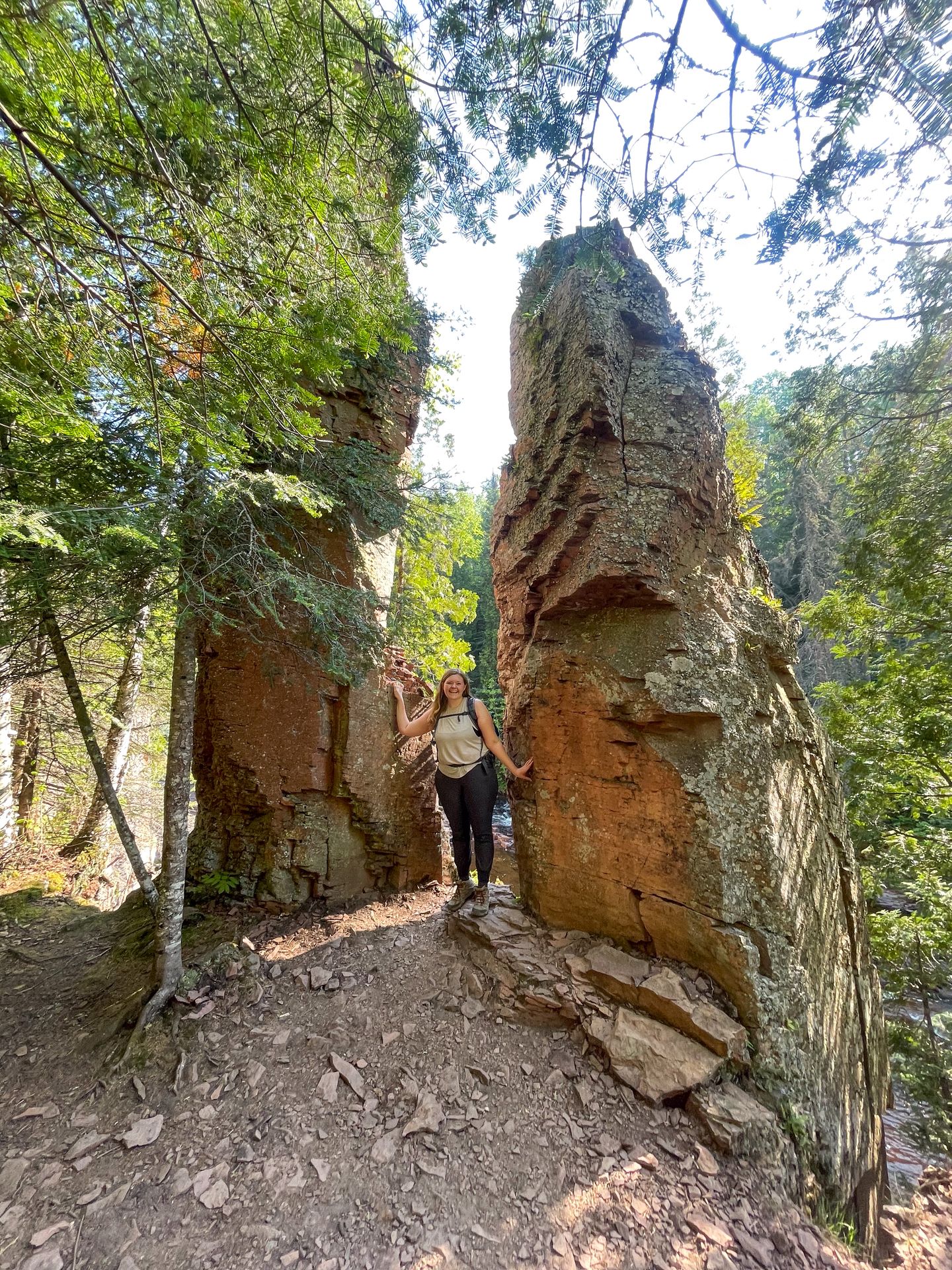 Lydia standing between two large rocks that seem to stick straight out of the ground.