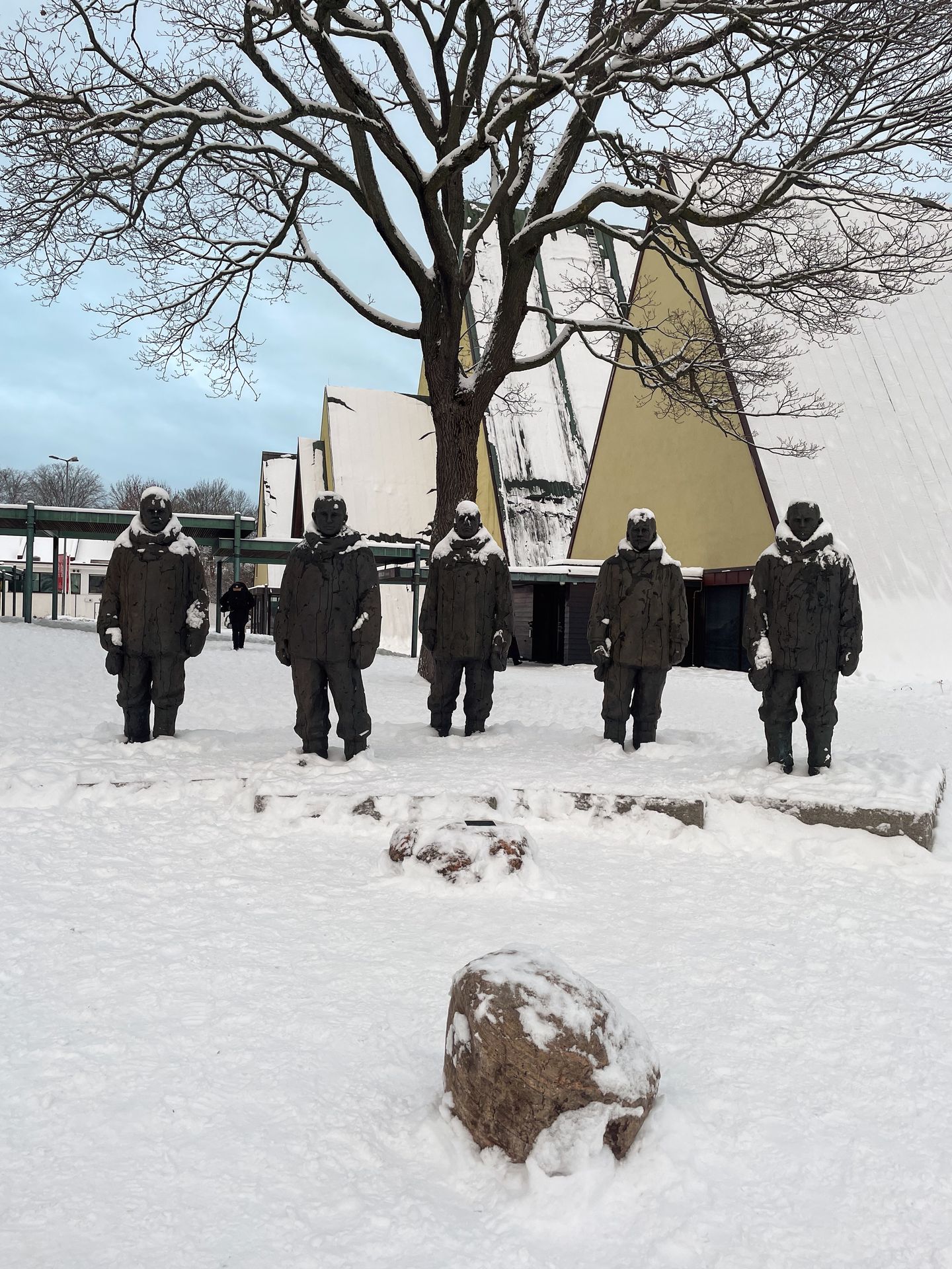 5 statues of life-sized human figures covered in snow in front of the Fram Museum