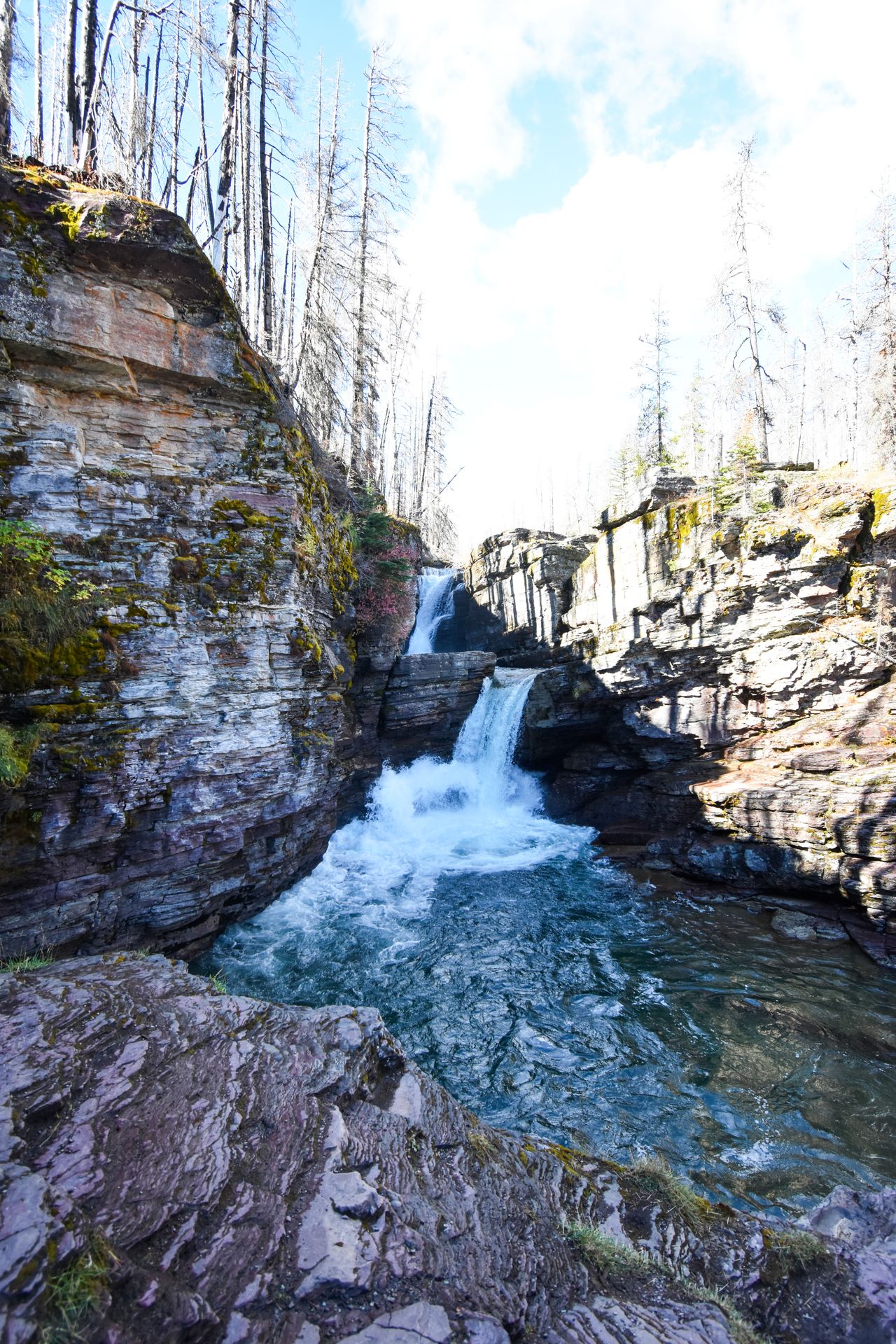 A two tier waterfall surrounded by rock walls.