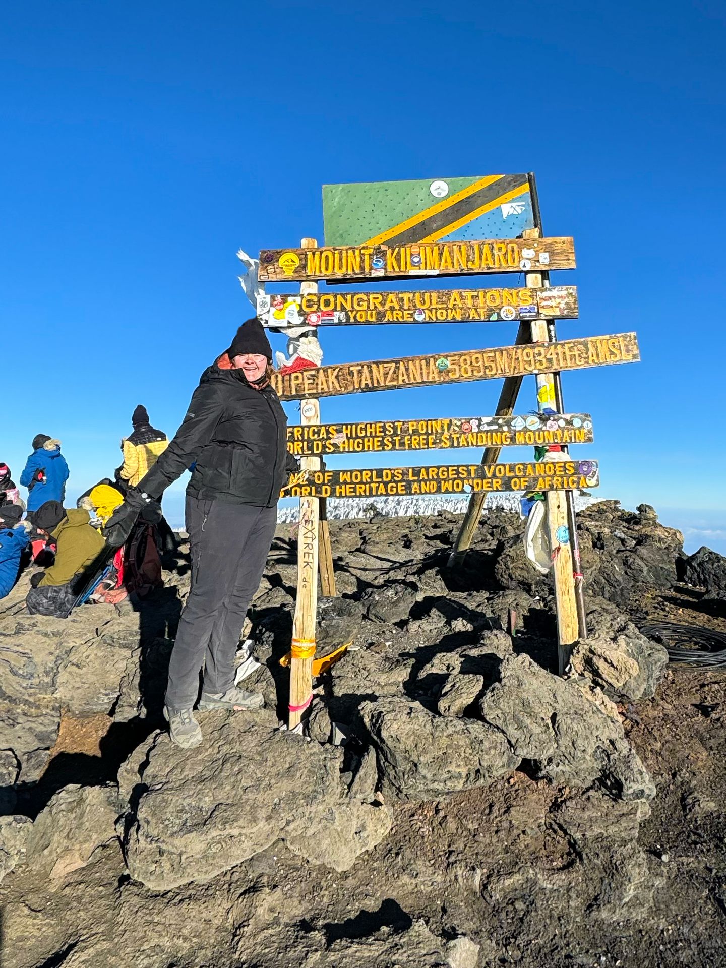 Lydia standing next to the sign at the summit of Mount Kilimanjaro