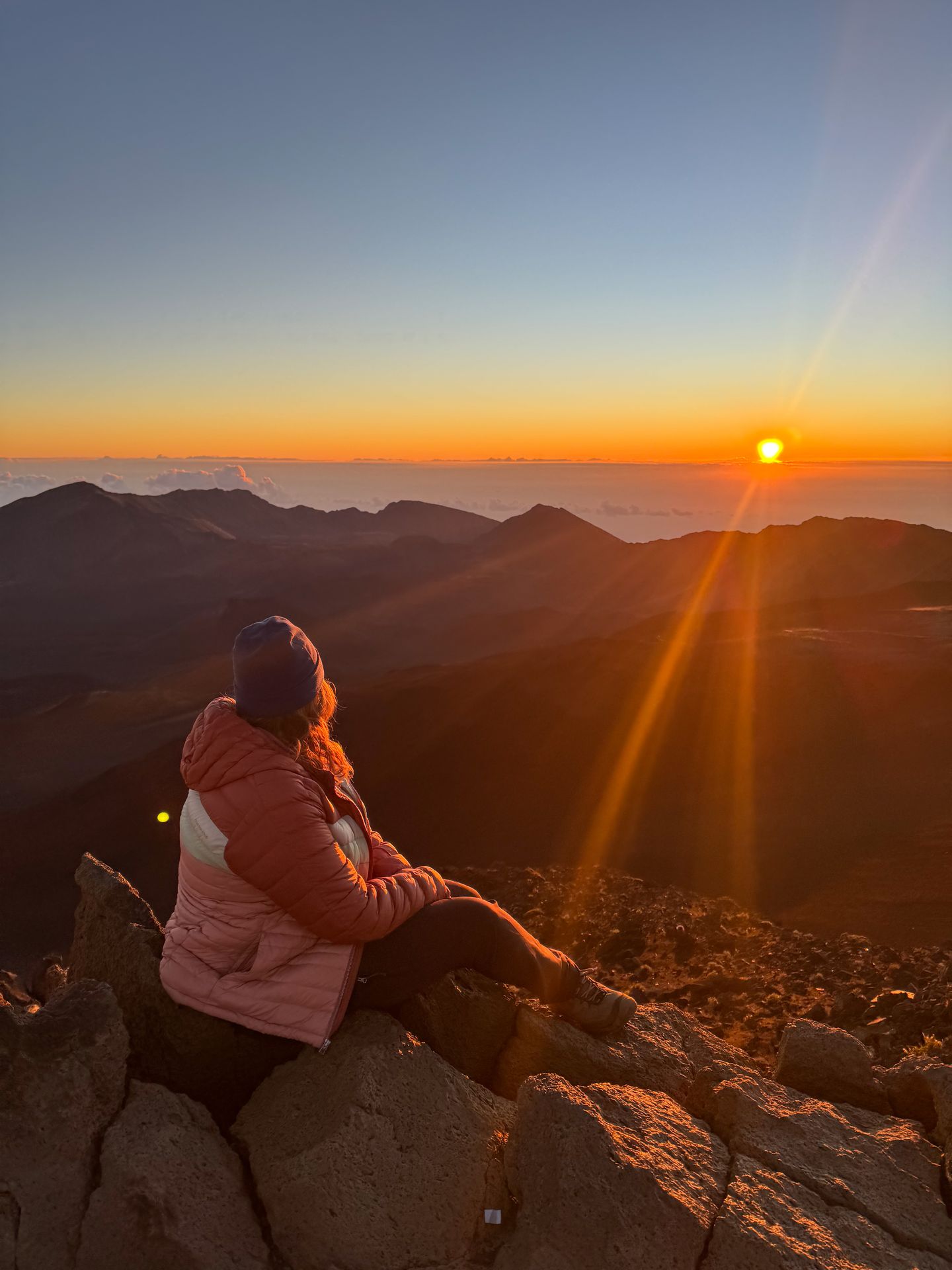 Lydia sitting and looking out over the crater at sunrise