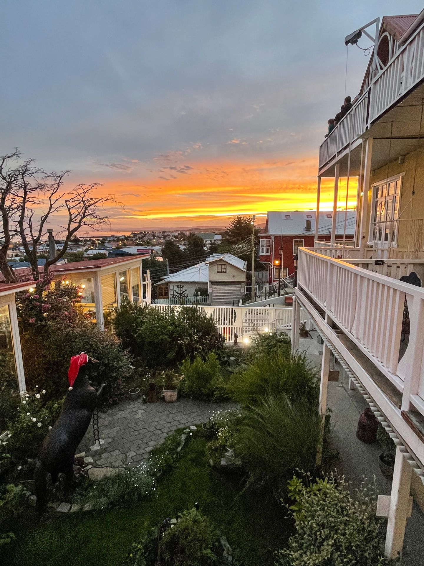 A sunset sky seen from the backcony of Hotel La Yegua Loca. The sky glows orange and there is a courtyard below with a horse statue wearing a santa hat.