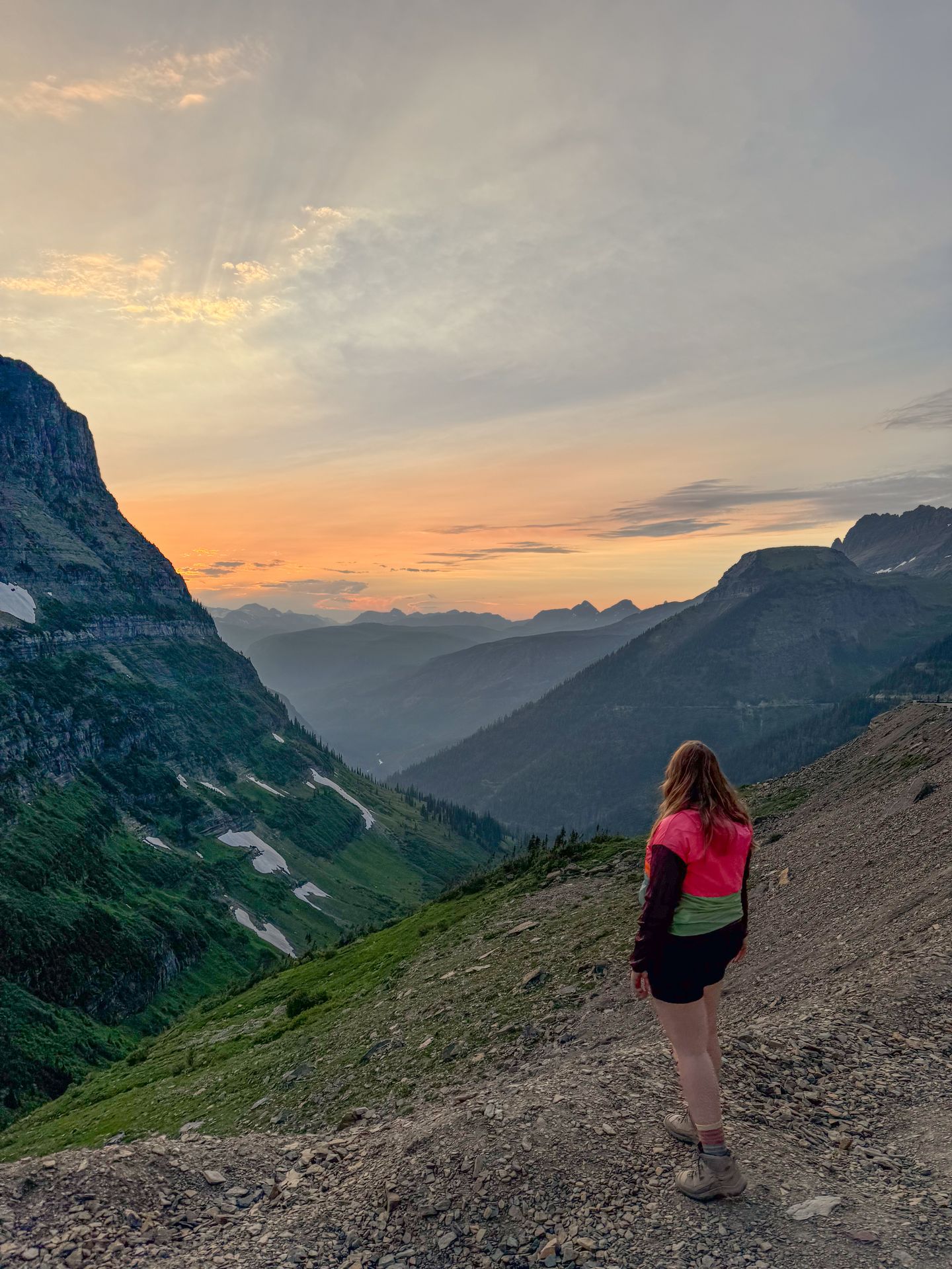Lydia standing and looking out at a sunset along the Going-to-the-Sun Road