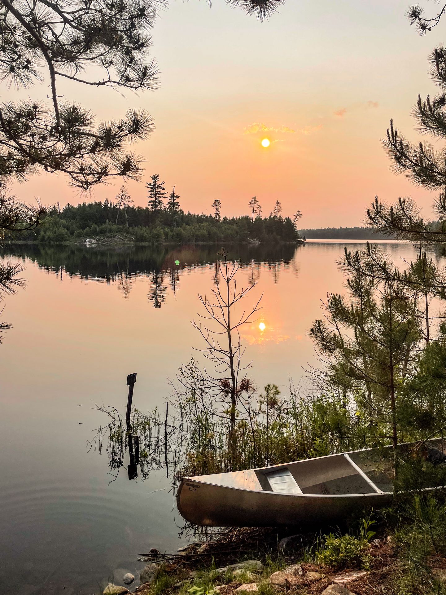 A canoe next to the water and a view of the sunset over the Shoepack Lakes in Voyageurs National Park