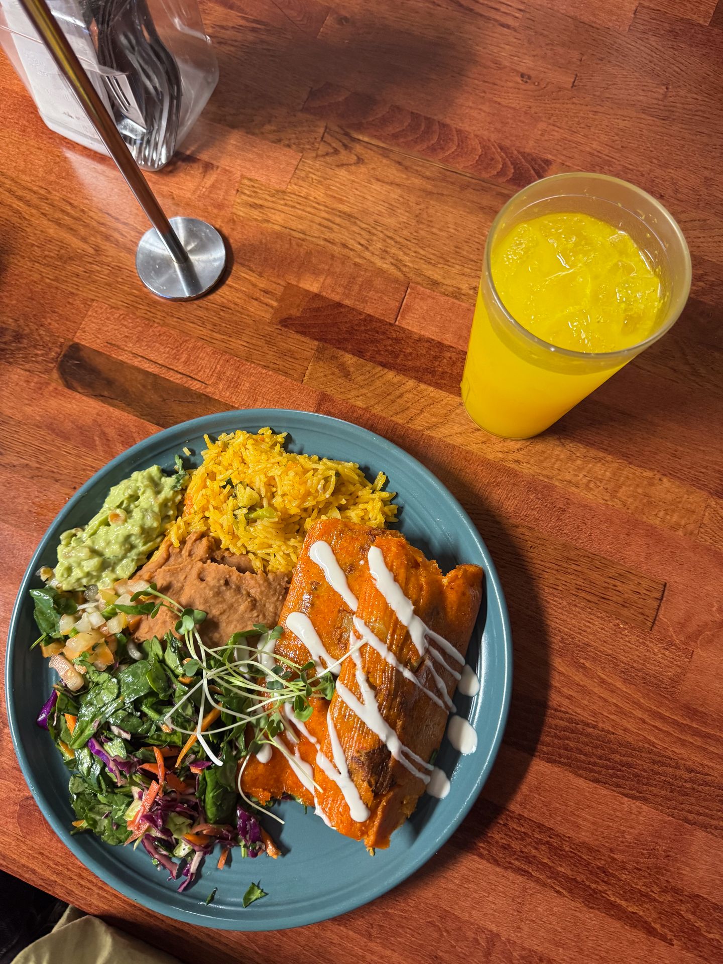 A plate with tamales and sides, plus a glass of juice