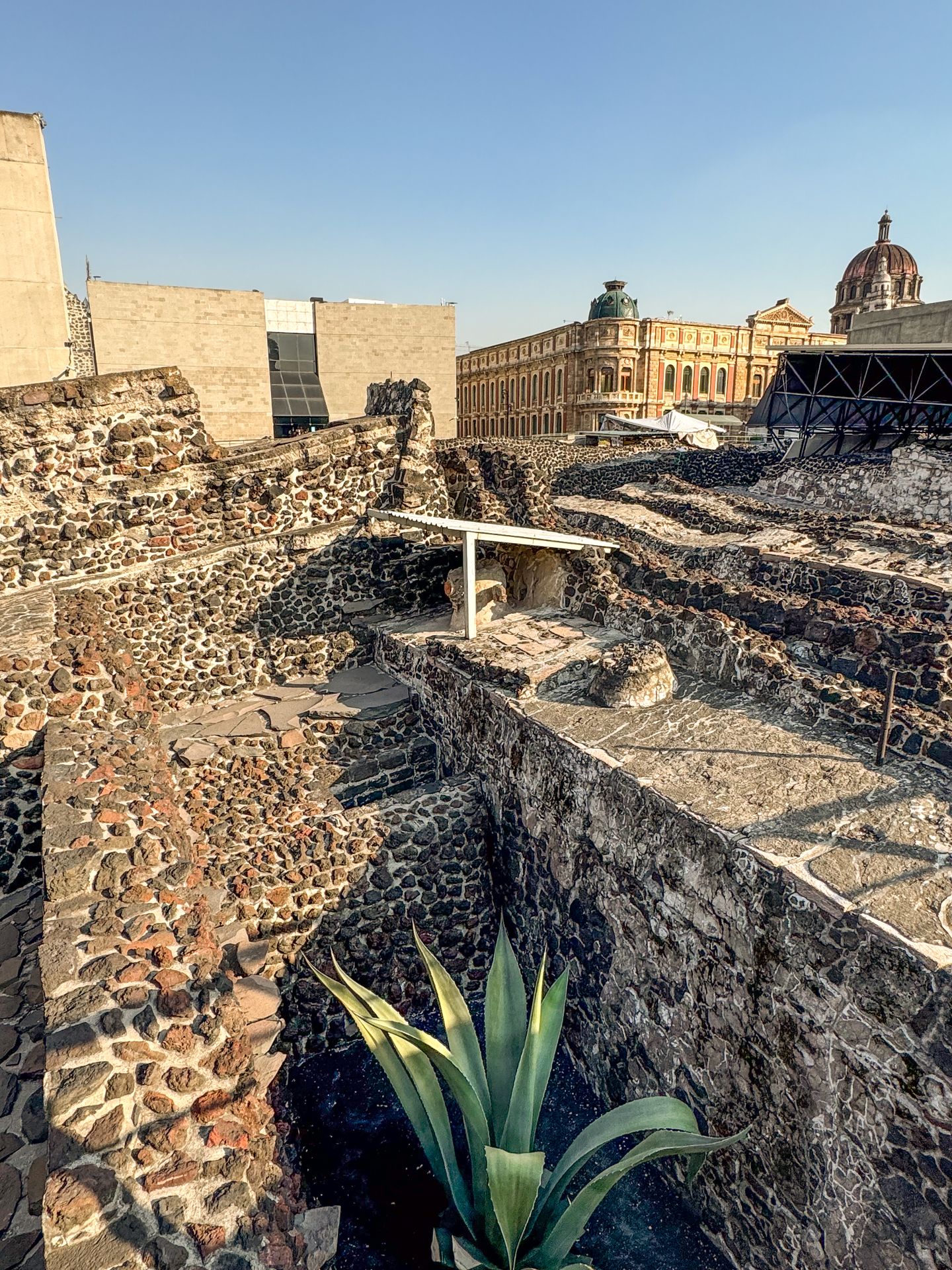 A large area full of stone ruins, with more modern buildings in the distance
