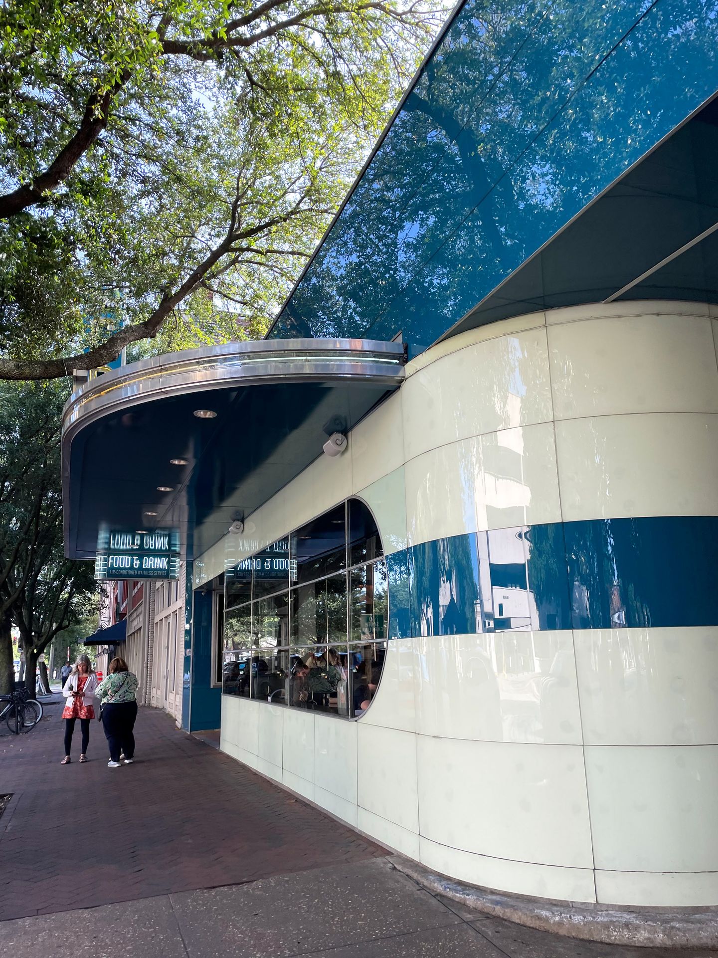 The exterior of the Grey. There are large blue and white stripes. The fancy restaurant is a former Greyhound bus station