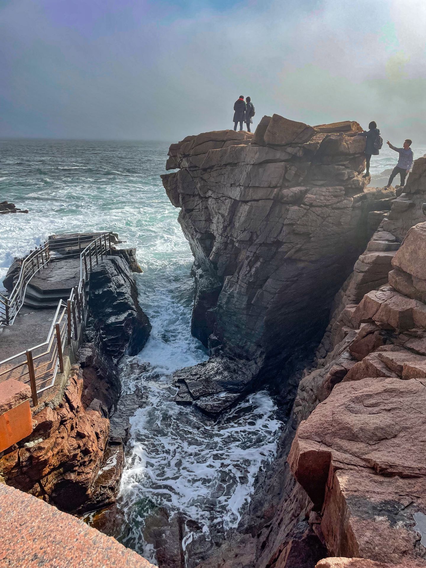 A whirlpool of water surrounded by tall rocks, with a viewing platform on the left.