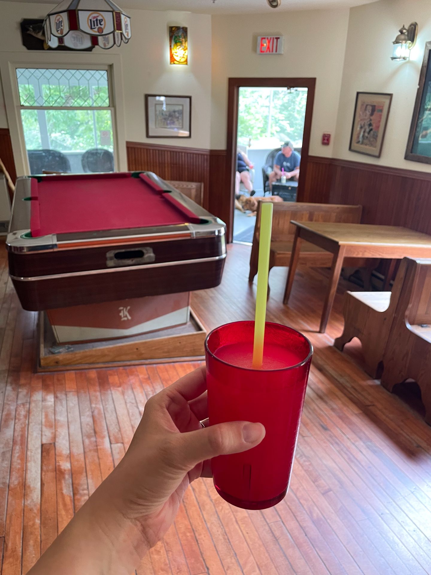 Holding up a drink in front of a pool table in the slanted bar at the Kettle Falls Hotel