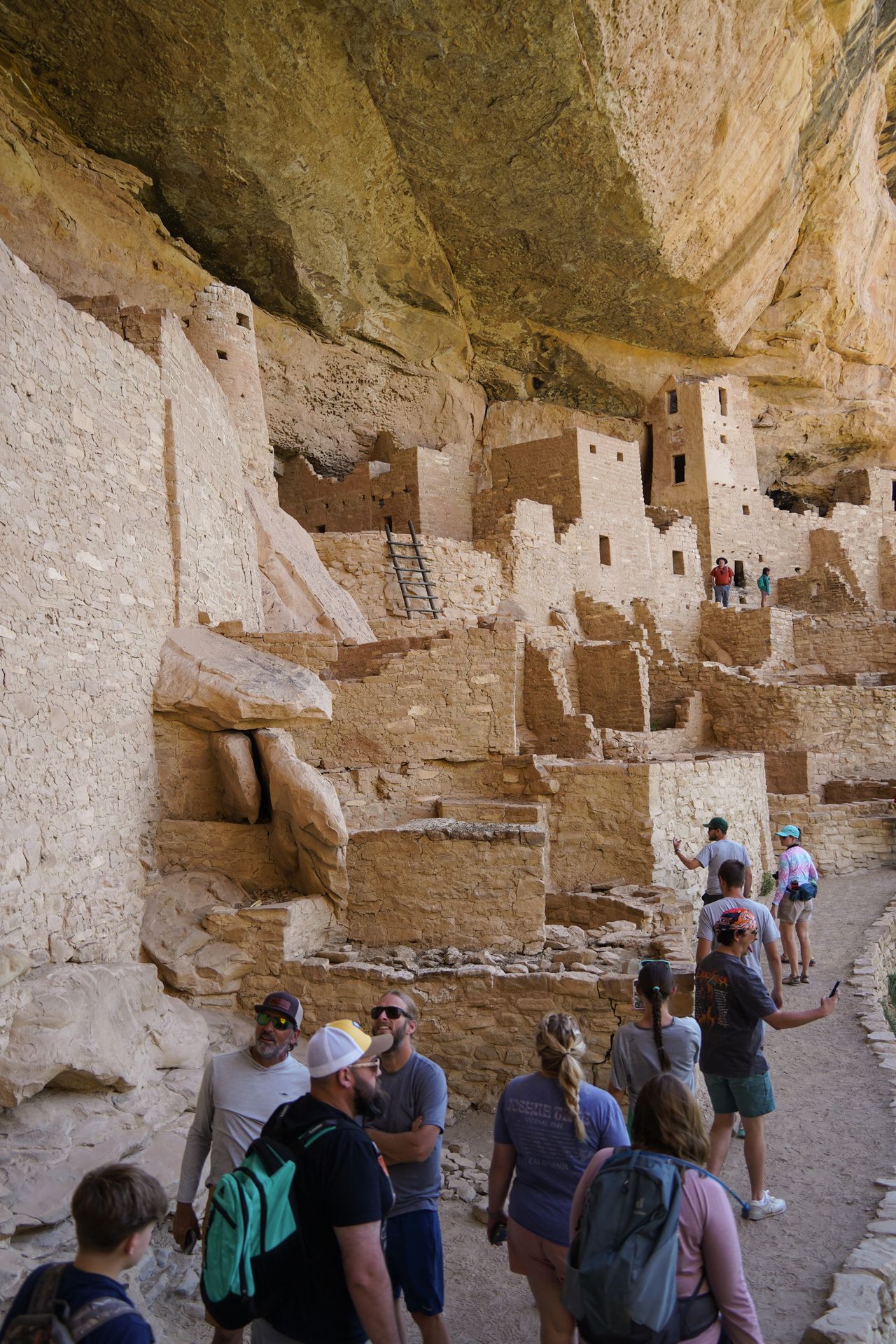 A group of people exploring and taking photos inside of Cliff Palace
