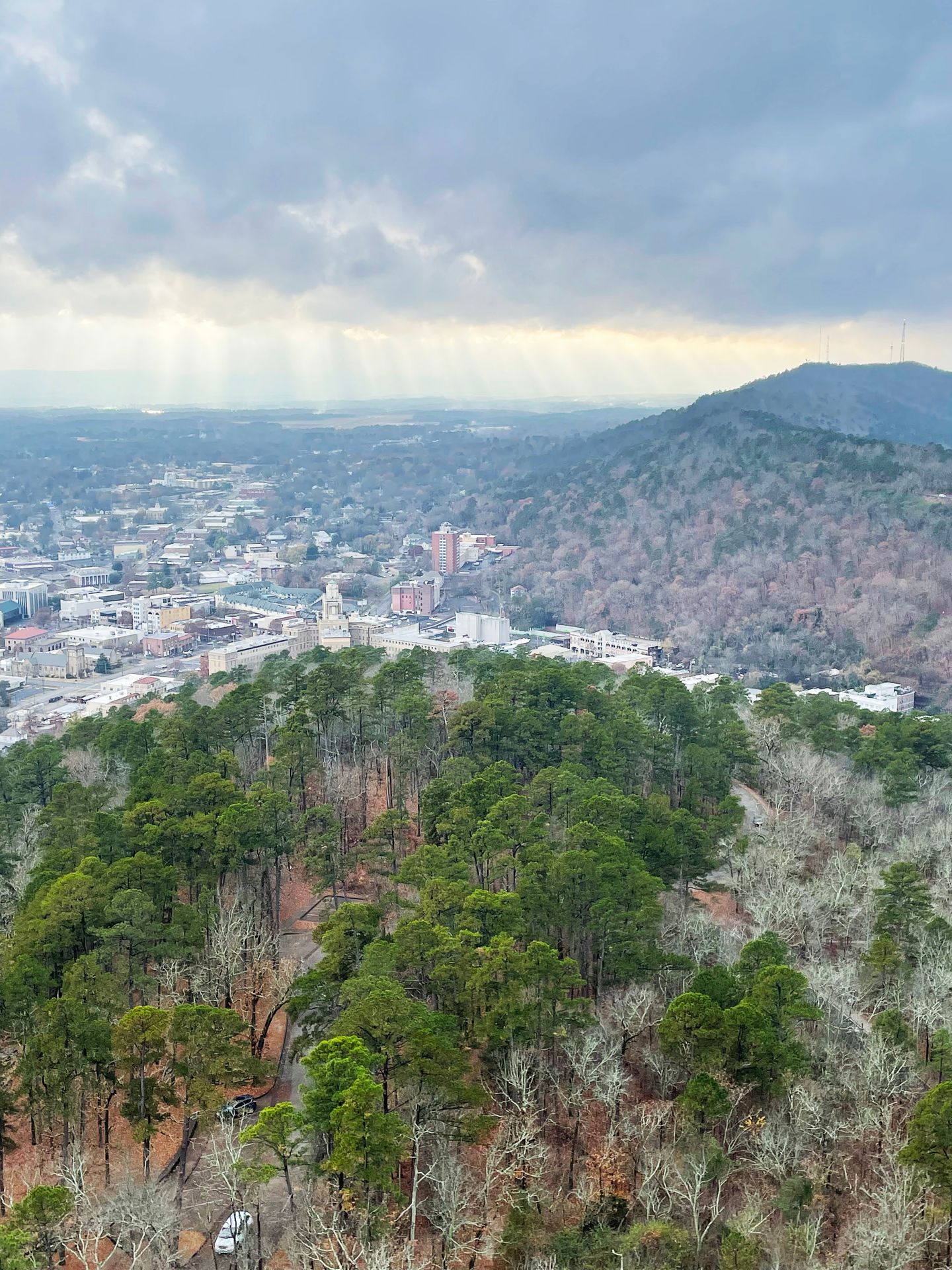 The view looking at downtown Hot Springs from the Hot Springs Mountain Tower. There is some red fall foliage on the hill behind the downtown area.