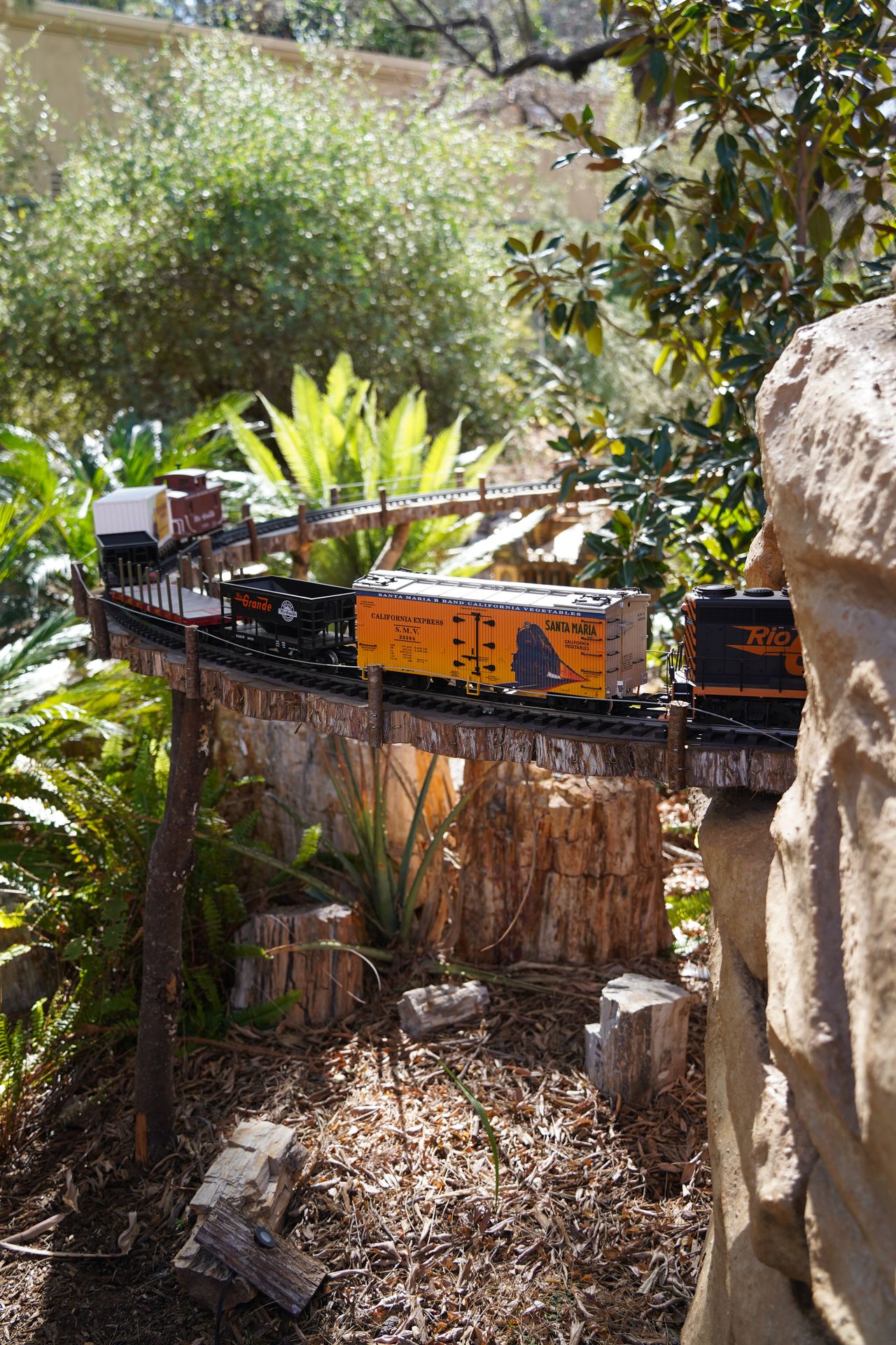 A small train riding by on an elevated track at the Tuccon Botanical Gardens