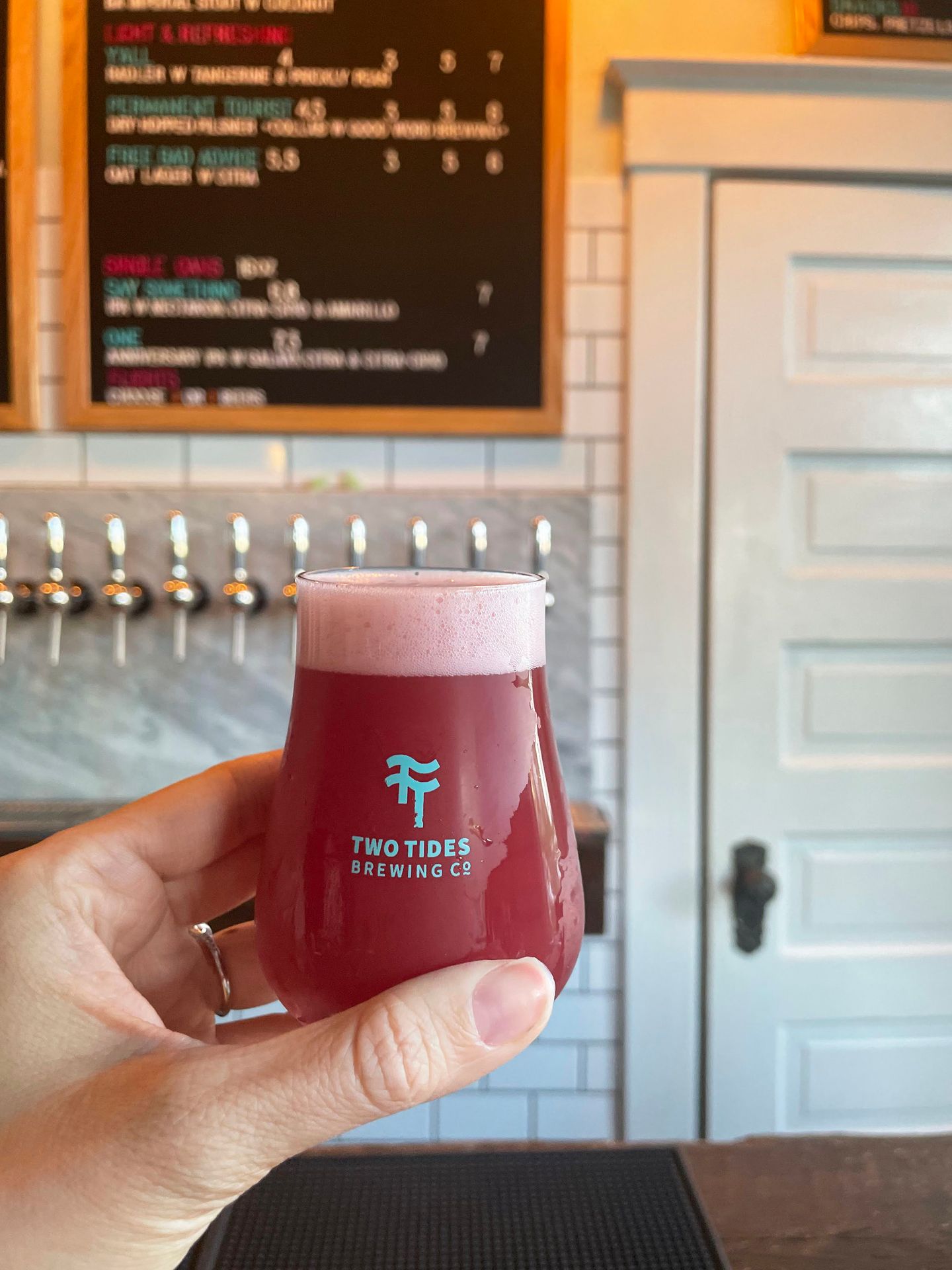 Holding up a red colored ber at Two Tides Brewery