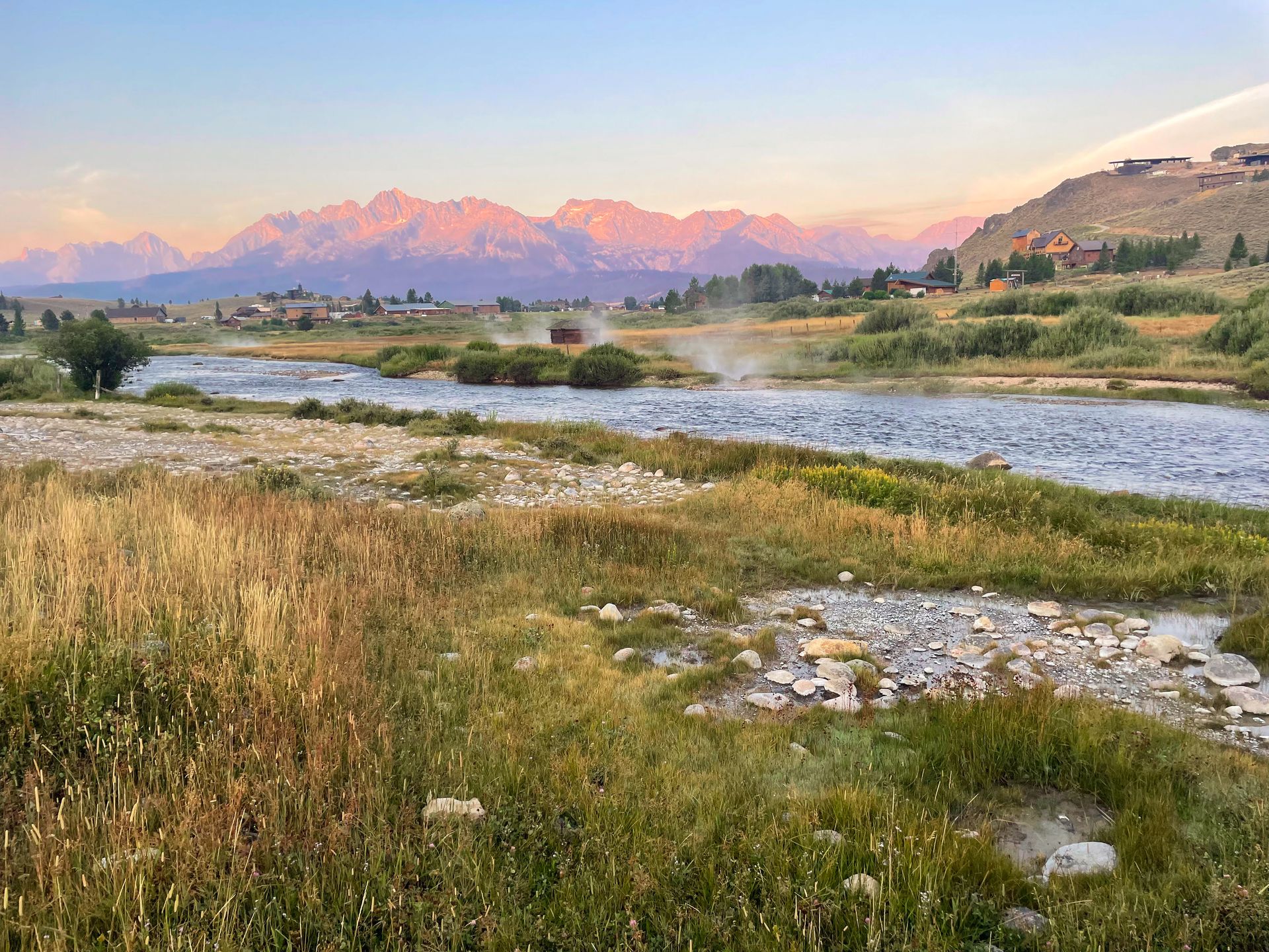 Looking at Valley Creek with the mountains in the distance during sunrise. The mountains are pink due to the light.