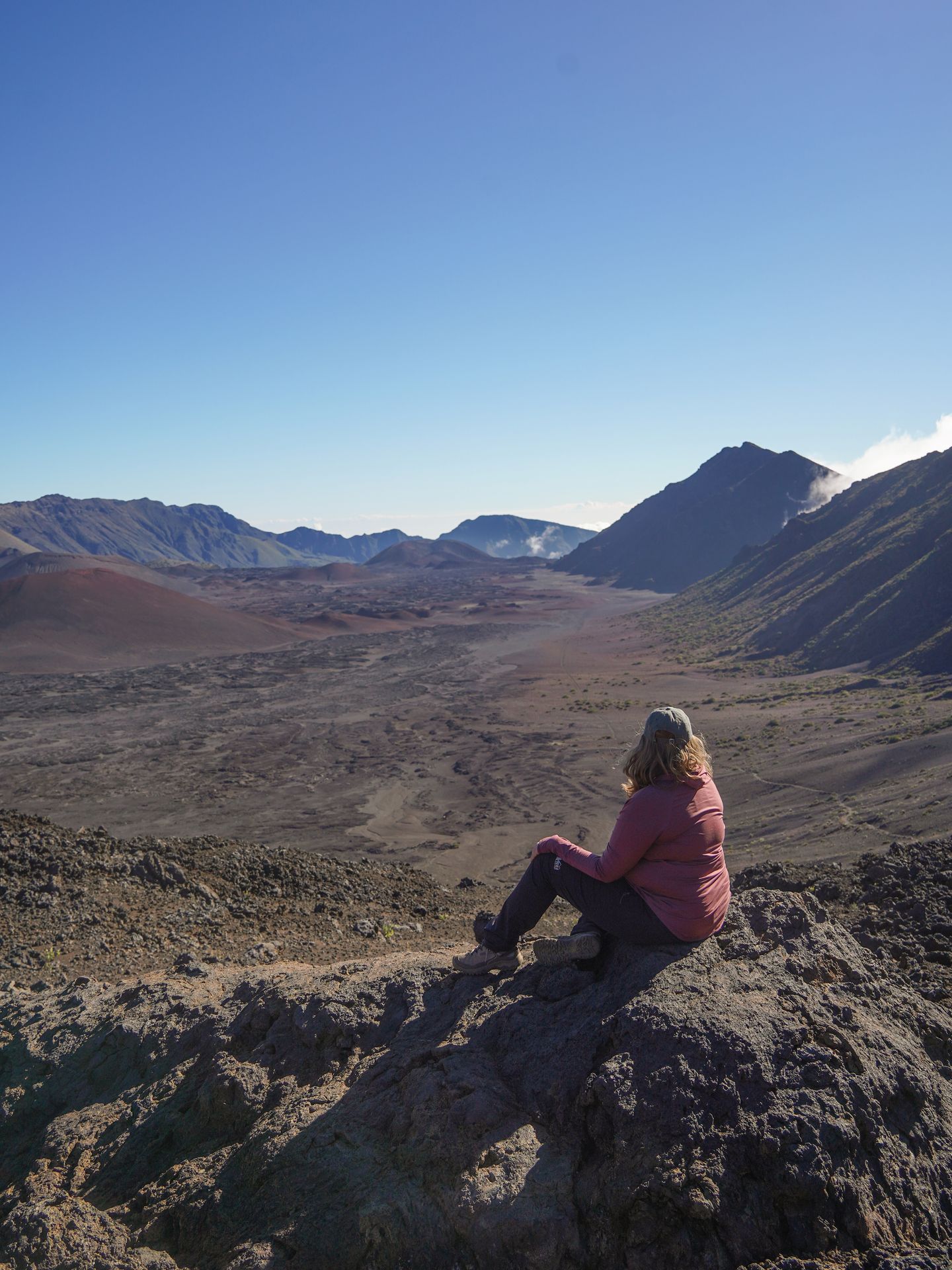 Lydia sitting on a rock and looking out a crater of Haleakala