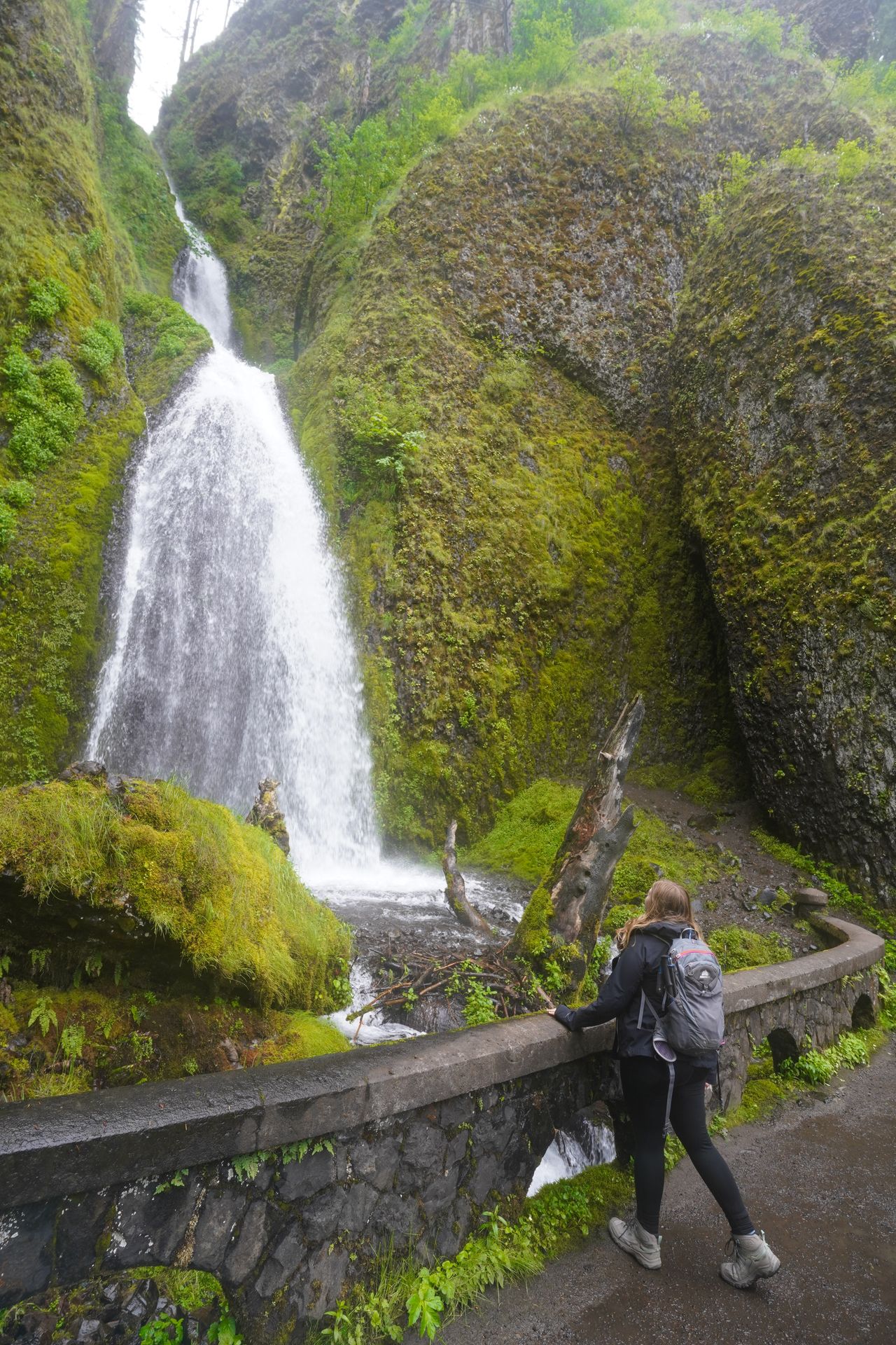 Lydia looking out at Wahkeena Falls from behind a stone wall