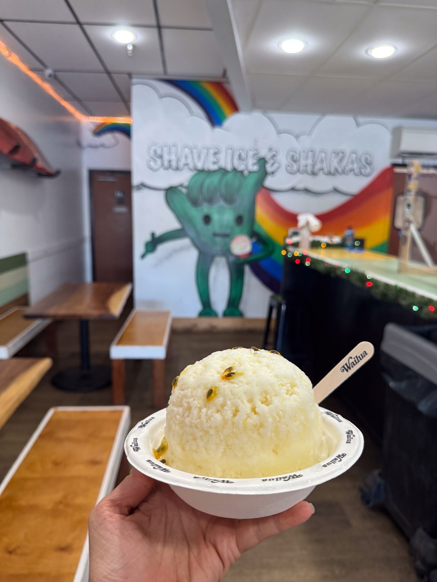 Passion fruit shave ice in front of a mural inside of Wailua Shave Ice