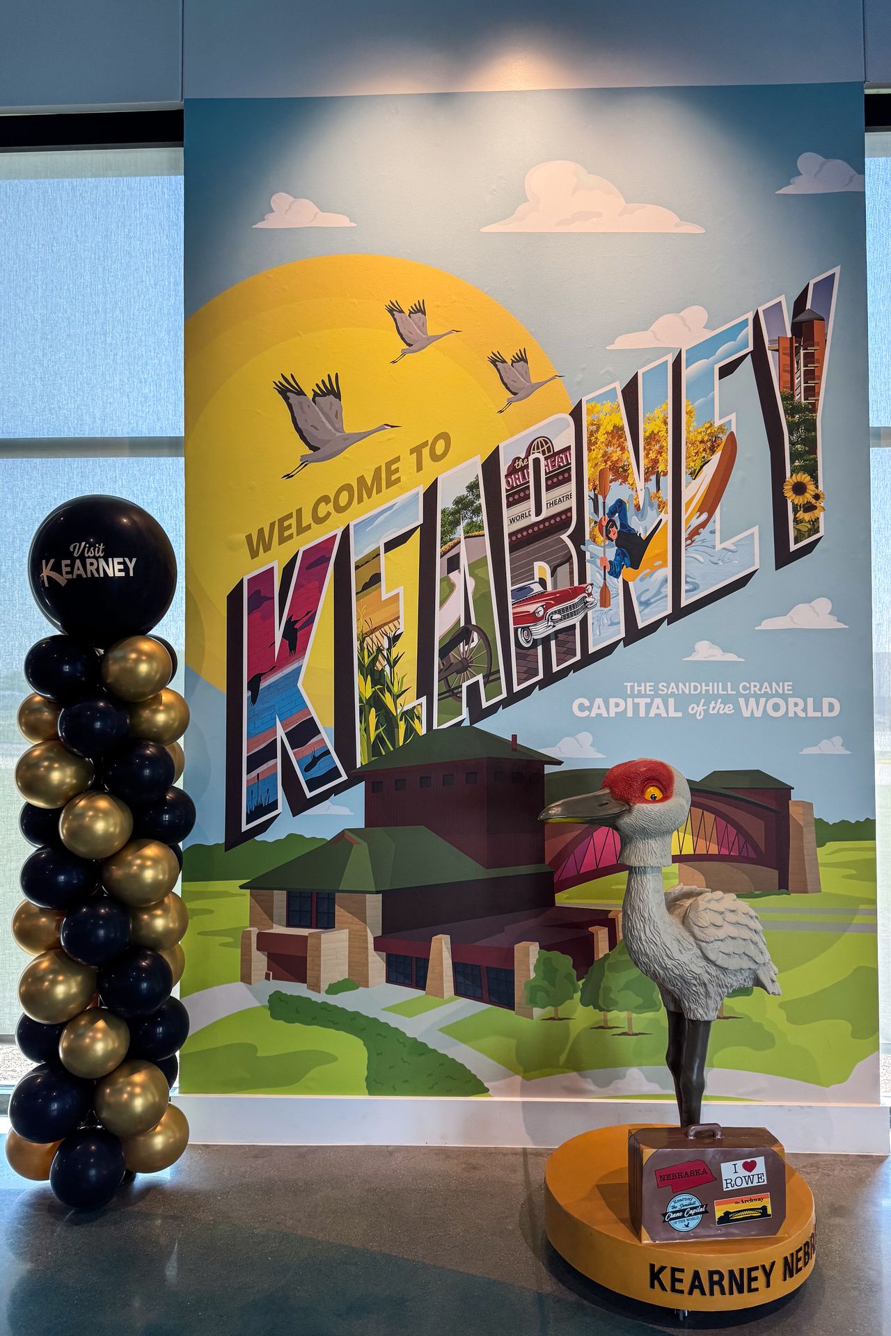 A welcome sign that reads 'Welcome to Kearney' with balloons next to it inside of the Kearney Welcome Center