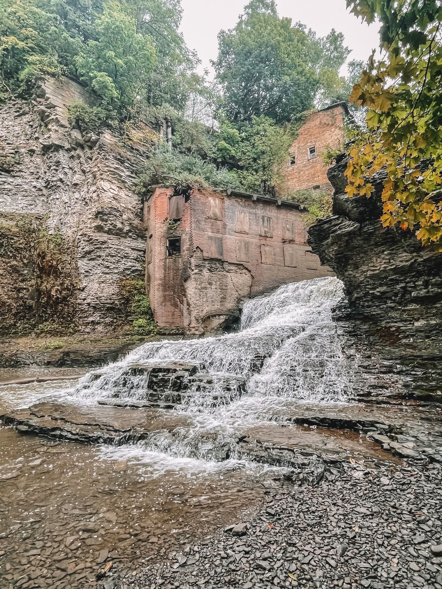 A waterfall flowing down rocks. A red building is built into the rock fall at one side of the falls.
