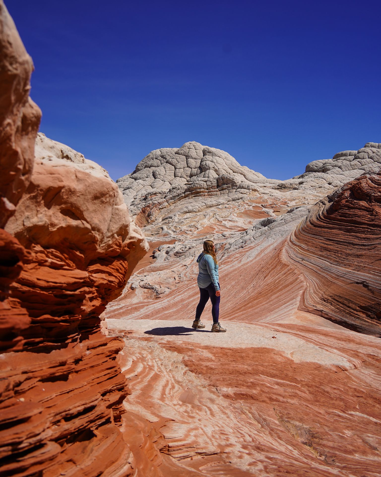 Lydia standing on a white area of rock, surrounding by orange rocks and interesting rock formations.