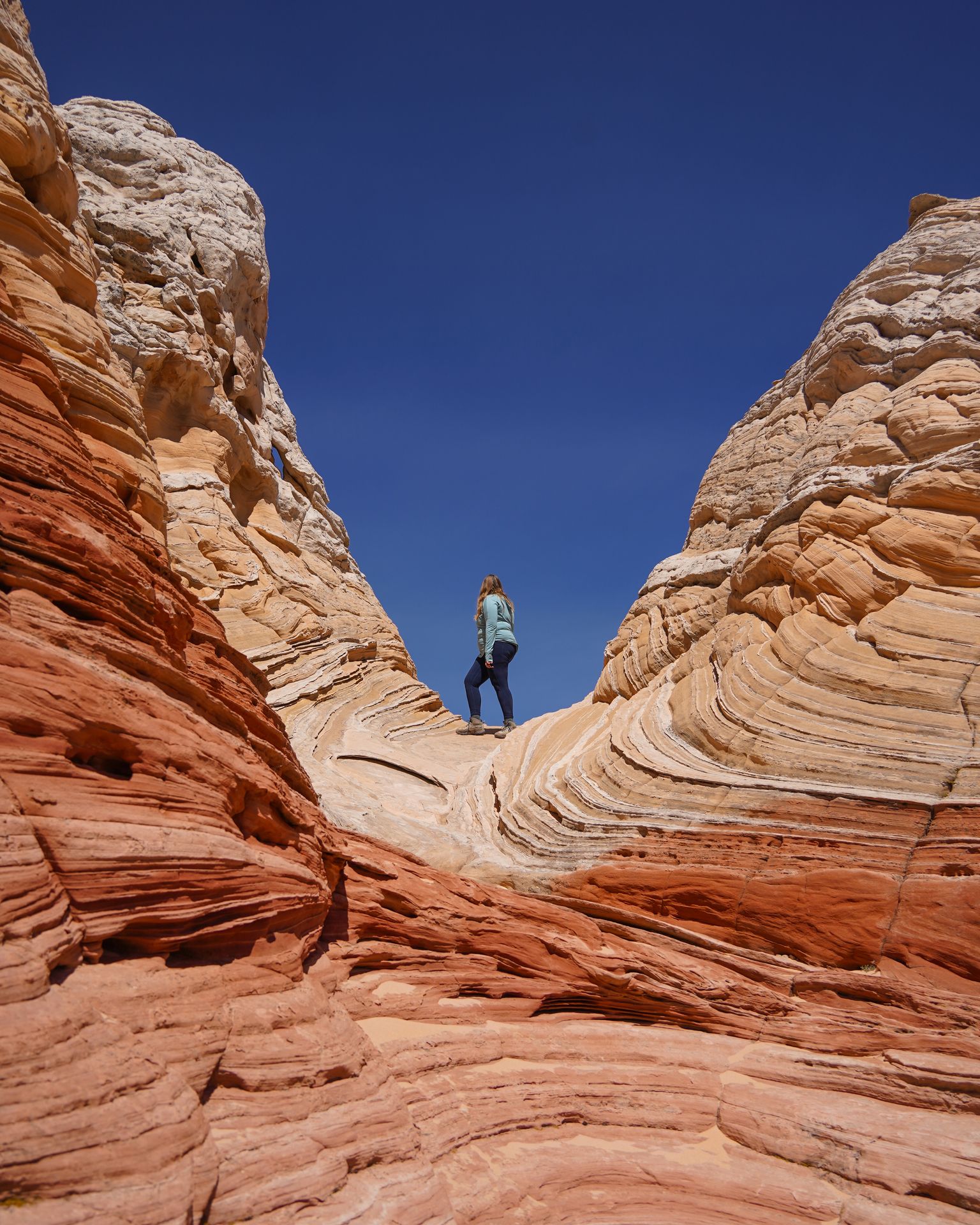 Lydia standing on a dip in the rocks, surrounding by an area of rock that look like the texture of a wave