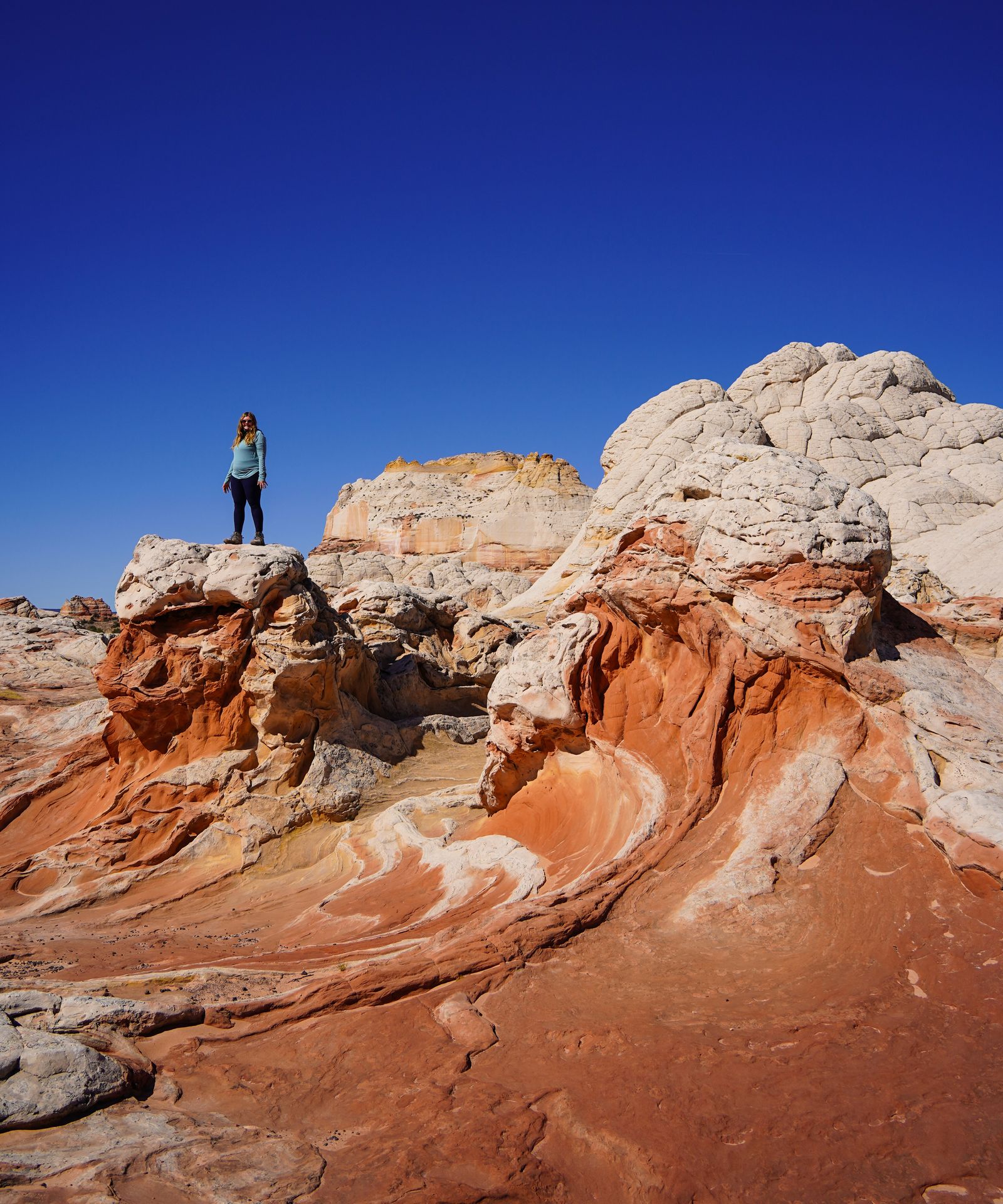 Lydia standing on a rock next to swirls of orange and yellow