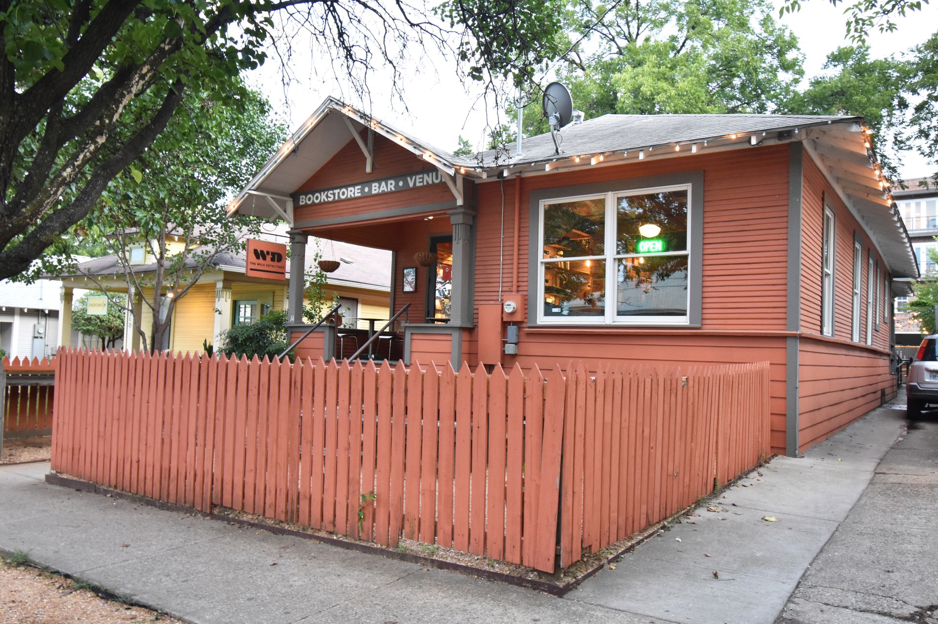 The exterior of Wild Detectives. The building is orange with a fence around the front patio space.