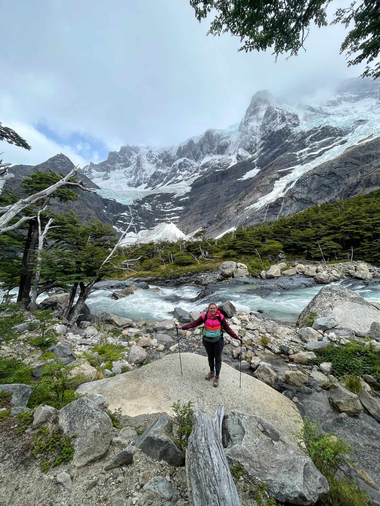 Lydia standing on a large rock next to a river with mountains in the distance